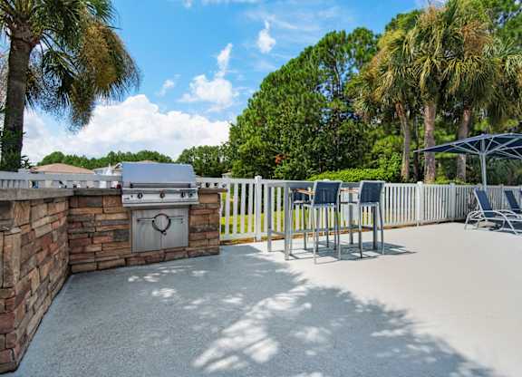 Outdoor grilling station with stone countertops and a seating area at Crystal Lake in Pensacola, Florida.