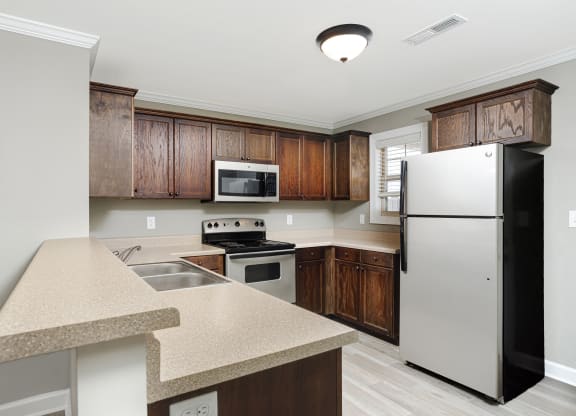 a kitchen with stainless steel appliances and wooden cabinets at The Oakley at Deerfield Apartments in Florence, AL