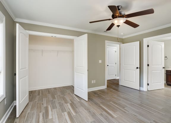 a bedroom with ensuite bathroom and ceiling fan and wood floors at The Oakley at Deerfield Apartments in Florence, AL