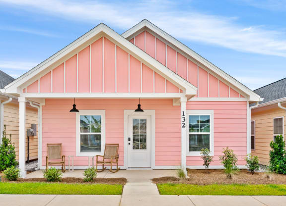 a pink house with two chairs in front of it at The Cottages at Foley Farms apartments in Foley, AL