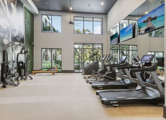 the gym with treadmills and windows at the estates at johnsons crossing