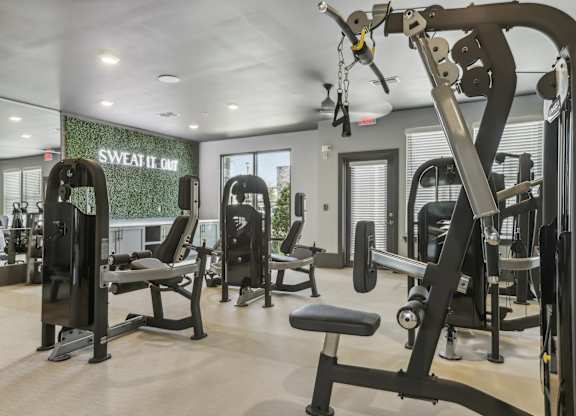 a gym with weights and cardio equipment and a sign on the wall