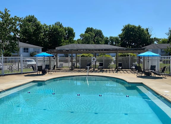A swimming pool with a fence and umbrellas around it.