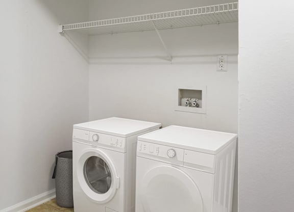 Two white front loading washing machines in a laundry room.