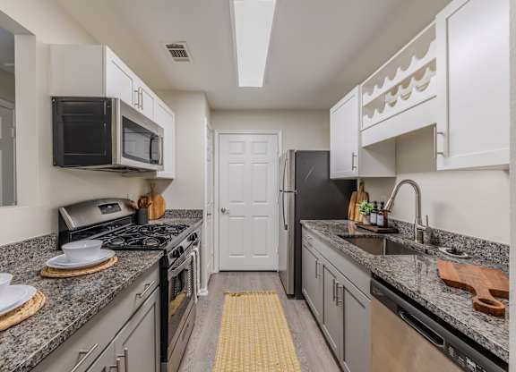 A kitchen with a black stove top oven and a black microwave above it at Grande View Apartments in Biloxi, MS
