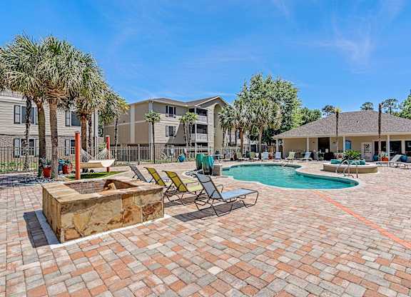 A sunny day at a residential complex with a pool and palm trees.
