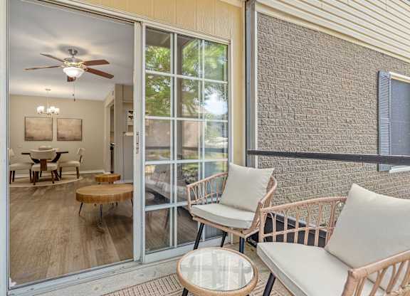 A patio with a table, chairs, and a ceiling fan.
