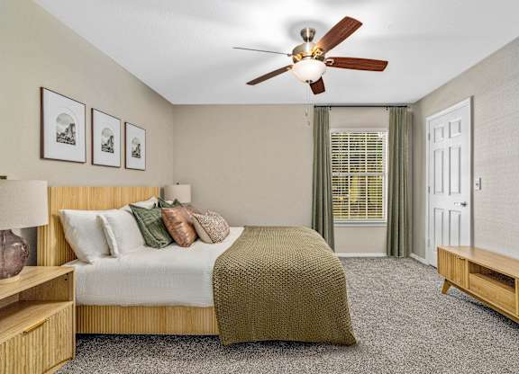 A bedroom with a bed, a ceiling fan, and a window with green curtains.
