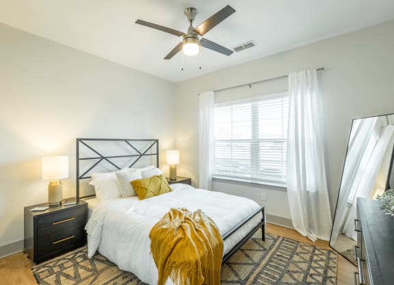 a bedroom with a large bed and a ceiling fan at Anthem Apartments and Cottages in Huntsville, Alabama