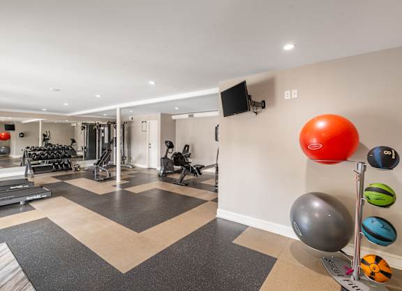 A gym with a variety of equipment including weights and exercise balls.