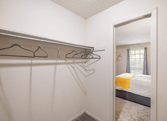 A white bedroom with a bed, a window, and a mirror.