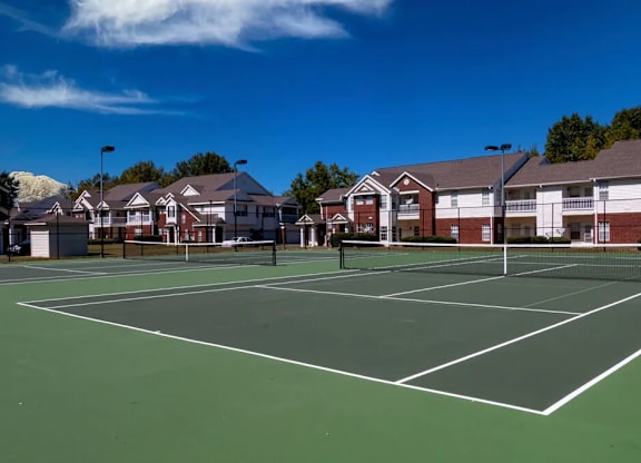 A tennis court is surrounded by houses.