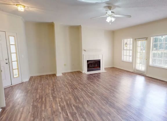 A spacious room with a fireplace and wood flooring.