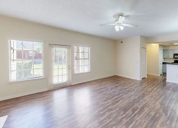 A spacious room with wood flooring and a ceiling fan.