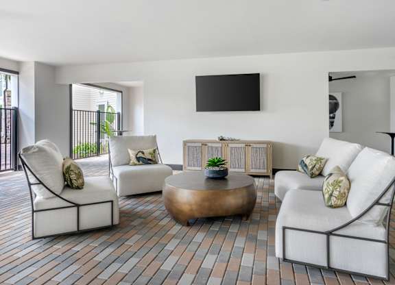 A living room with white furniture and a flat screen TV mounted on the wall.