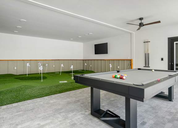 A pool table in a room with a television and a fan.