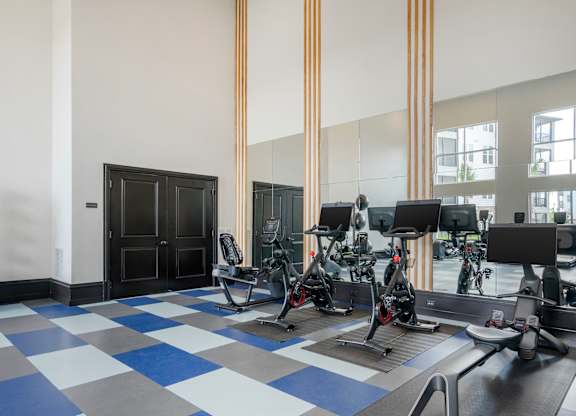A gym with a row of exercise bikes and a black door.