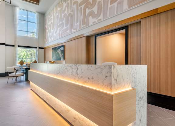 A reception area with a marble counter and wooden lighting.
