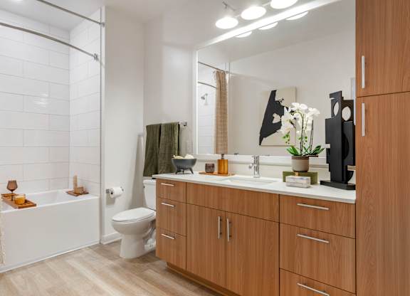 A modern bathroom with a white toilet, a white sink, and a white bathtub.