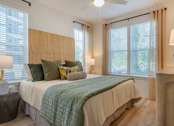 A bedroom with a bed, two lamps, and a window with blinds.