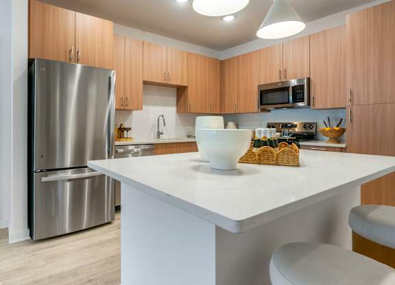 A modern kitchen with a white countertop and wooden cabinets.