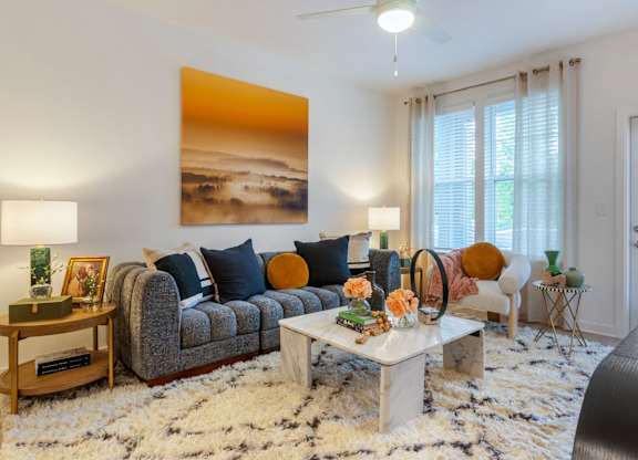 A living room with a grey couch, a coffee table, and a painting on the wall.