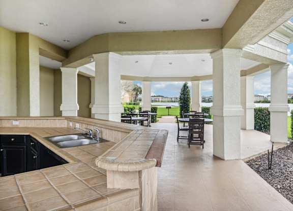 a large porch with a sink and a patio with tables and chairs