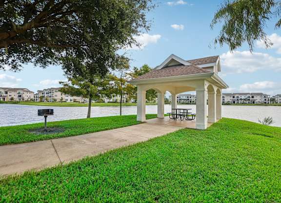 a gazebo with a picnic table on the grass next to the water