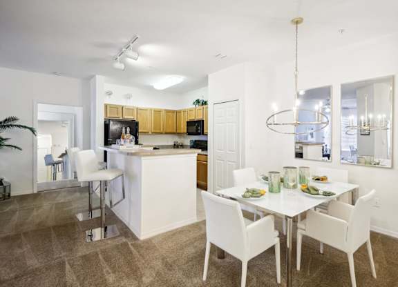 a dining room and kitchen with a white table and chairs
