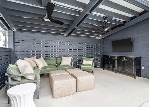 A living room with a green couch, a white table, and a television.