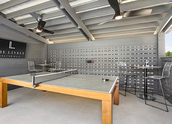 A ping pong table is in the middle of a room with a sign that says "The Lively Drayton Mills.".