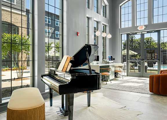 A grand piano sits in a room with a lot of windows.