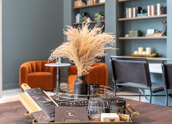 A table with a vase of dried flowers and a tray of soaps.
