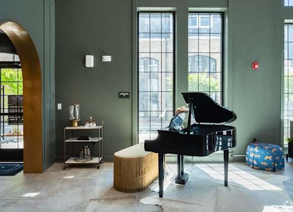 A grand piano sits in a room with a green wall and a large arched doorway.