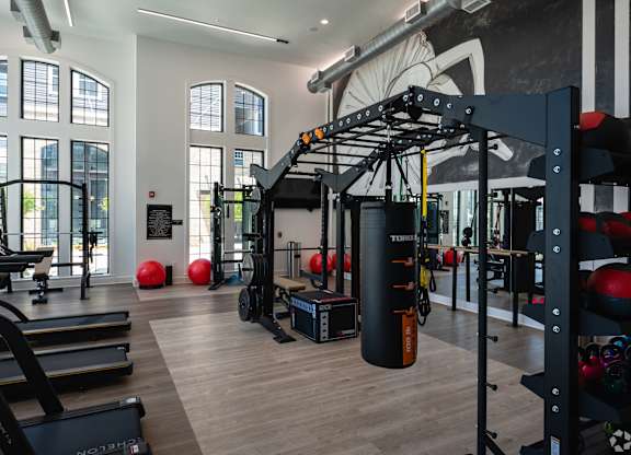 A gym with a variety of equipment including treadmills, weights, and a punching bag.