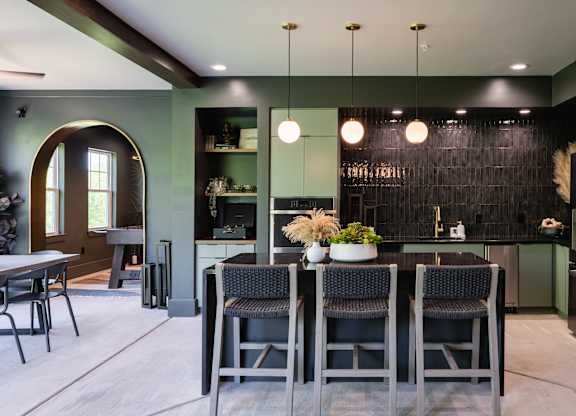 A modern kitchen with a dark green backsplash and a dining table with four chairs.