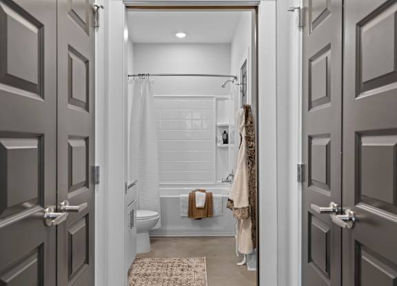 A bathroom with a toilet, a shower, and a towel hanging on the wall.