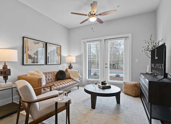 A living room with a brown leather couch, a wooden chair, a coffee table, and a flat screen TV.