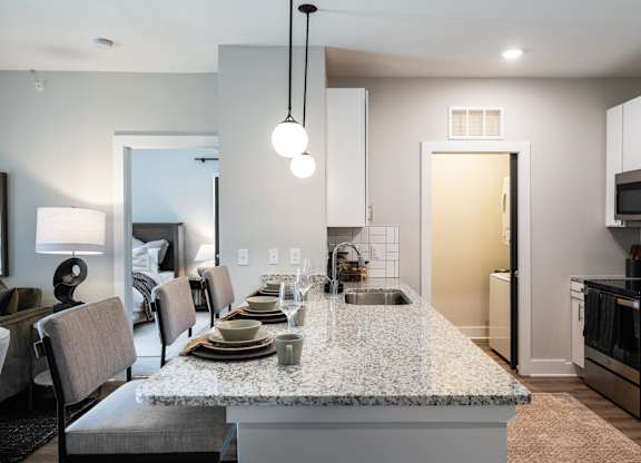 A kitchen with a granite countertop and a dining table with chairs.