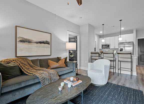 A modern living room with a grey couch, a coffee table, and a painting on the wall.