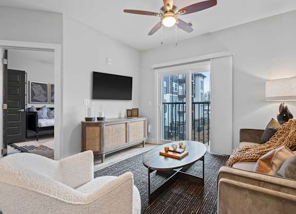 A living room with a white chair, a brown couch, and a ceiling fan.