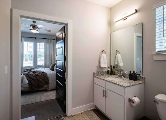 A bathroom with a bedroom door open to the bathroom.