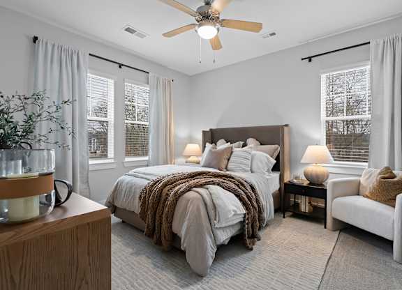 A bedroom with a bed, a chair, and a ceiling fan.
