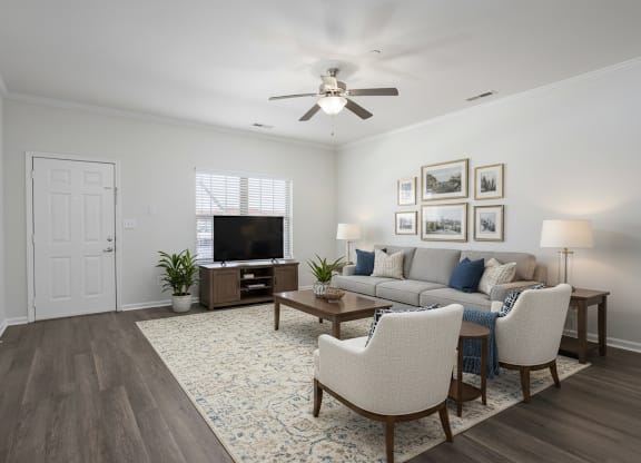 A living room with a white couch, a wooden coffee table, and a television.