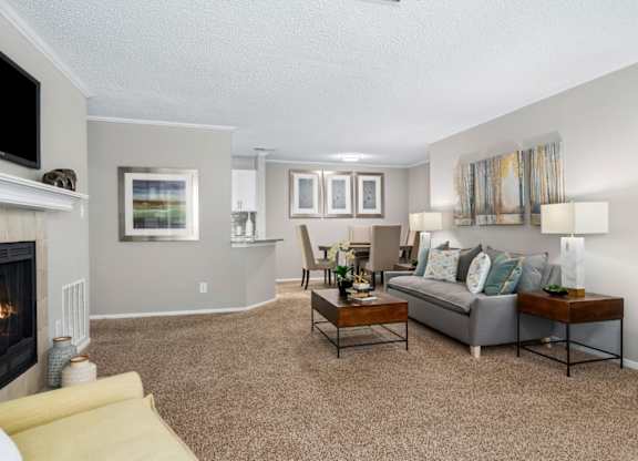 A carpeted open-concept living room with a fireplace at Summerchase at Riverchase in Hoover, Alabama.