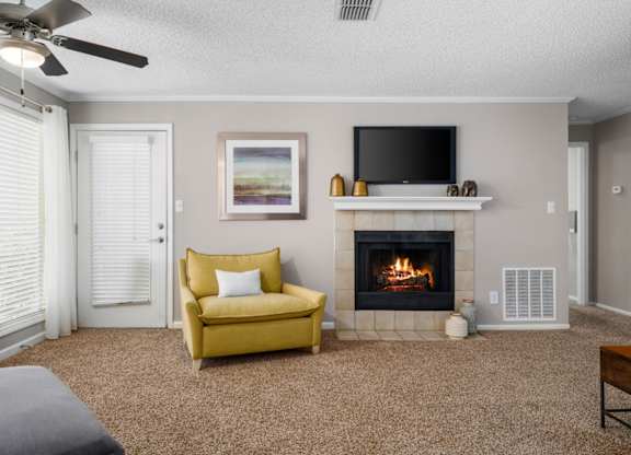 A carpeted living room, a ceiling fan, and a tile-surround fireplace at Summerchase at Riverchase in Hoover, Alabama.