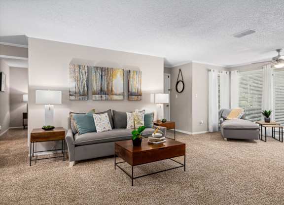 Living room with carpet and natural light A carpeted living room with a ceiling fan and floor to ceiling windows with natural light at Summerchase at Riverchase in Hoover, Alabama.