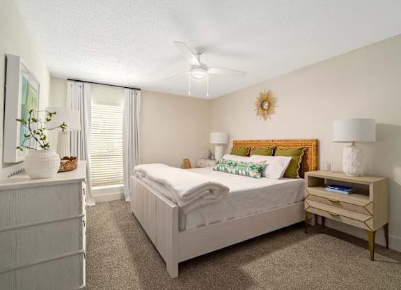 A bedroom with a bed, nightstand, and a plant on the dresser.