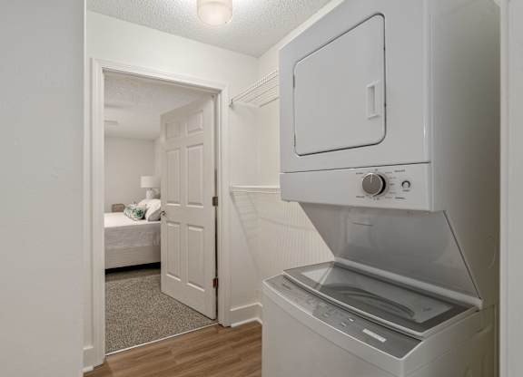 A white oven with a door open is in a room with a bed in the background.