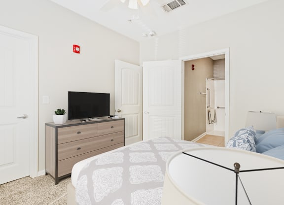 A bedroom with a bed, dresser, and television.